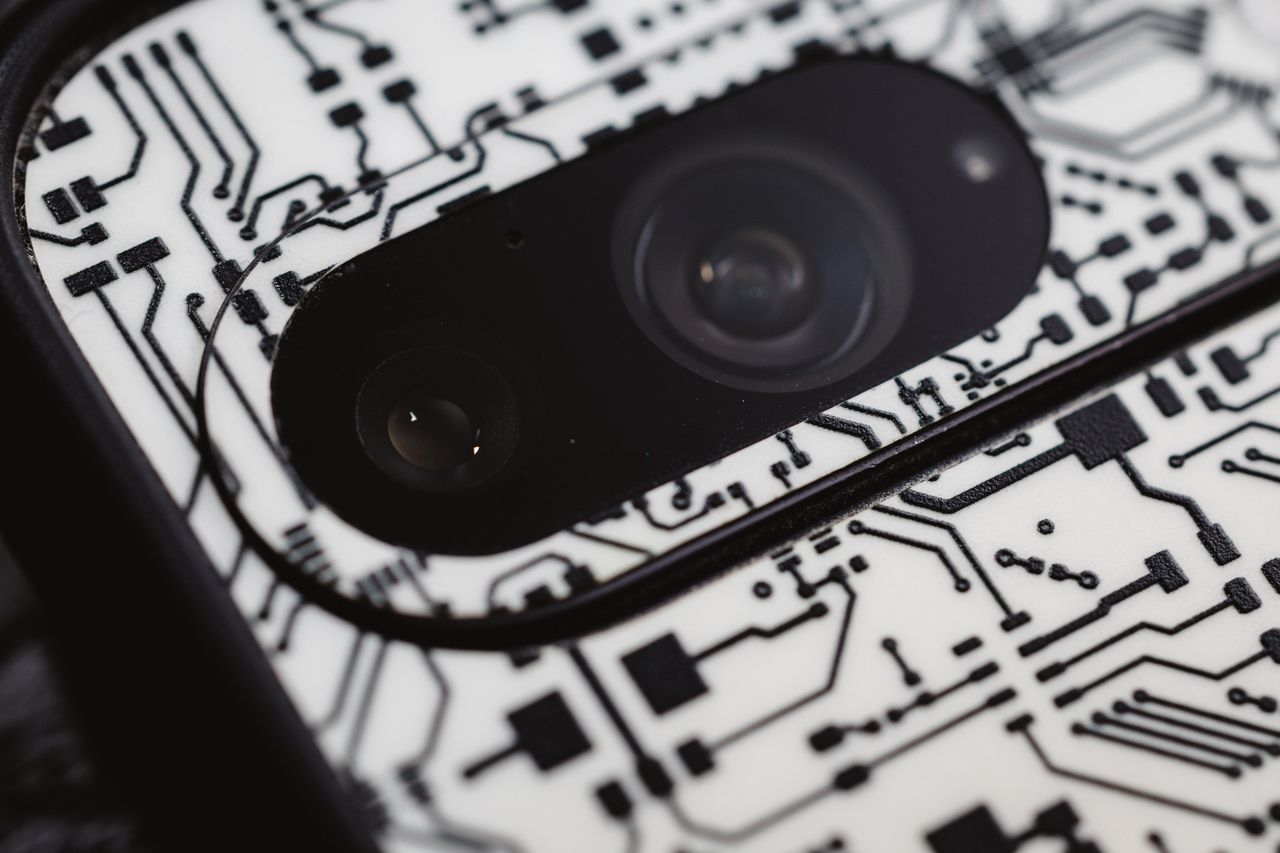 Macro shot of an electronic circuit design around a smartphone camera lens, showing intricate details.