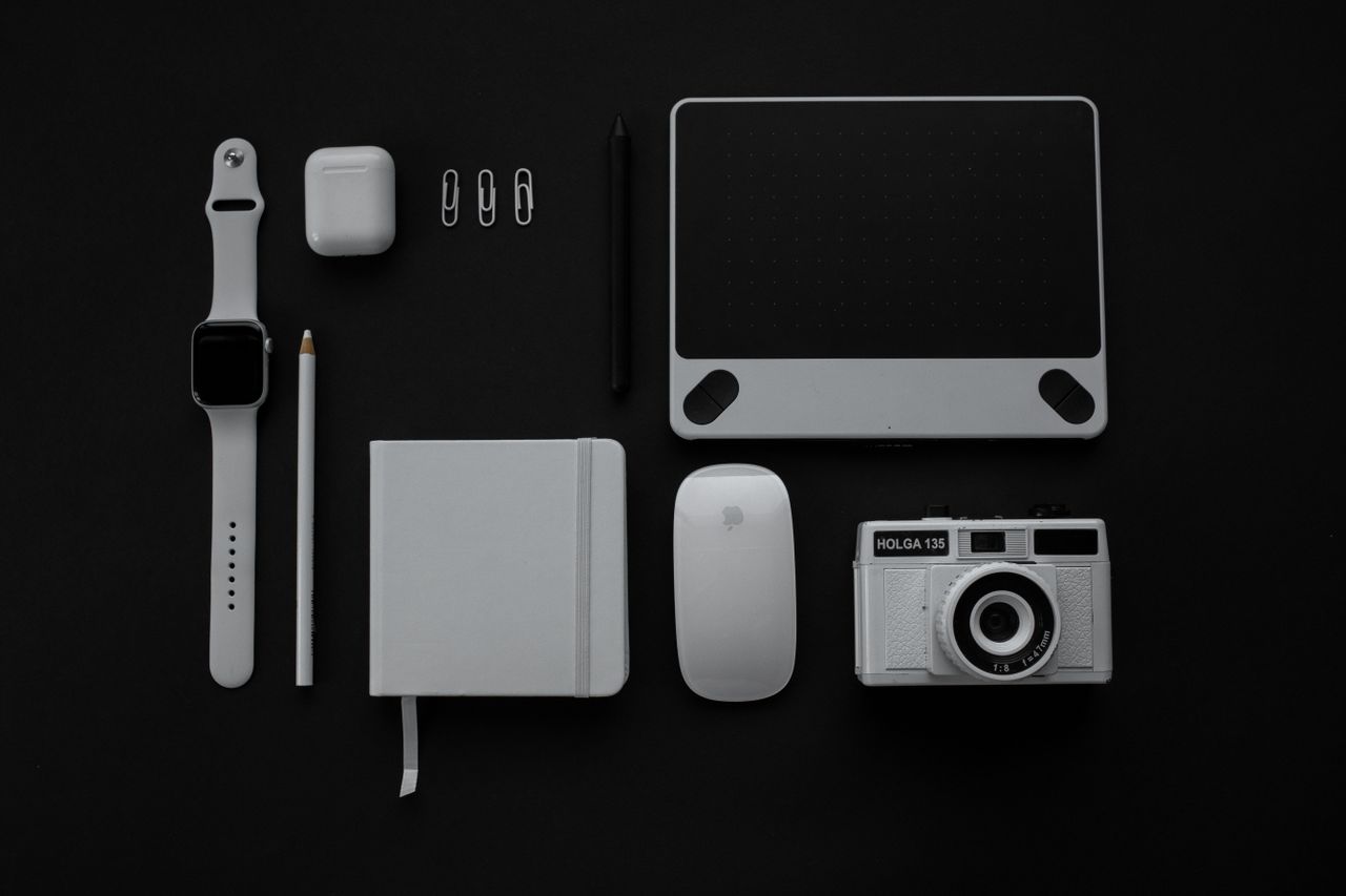 why-choose-us Flat lay of modern gadgets and accessories against a black background.